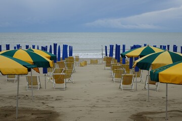 Fototapeta na wymiar THE END OF THE SUMMER. SHORE WITH UMBRELLAS AND DECK CHAIR ON THE BEACH.