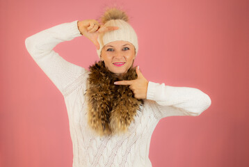 Portrait of a happy young woman dressed in winter clothes standing isolated over pink background