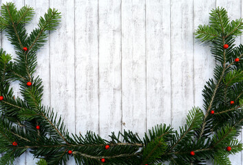 Weihnachtshintergrund, Rahmen aus grünen Tannenzweigen, roten Beeren, Geschenk auf weißem Holz...