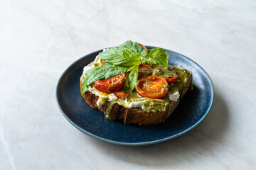 Healthy Toast Tartine with Cream Vegan Cashew Cheese Truffle Flavored, Pesto Sauce and Cherry Tomatoes.