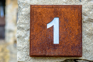Number one on a rusted squared house sign