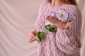 Young woman in knitted sweater holds a white flower. Close-up photo.