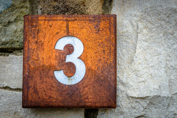 Rusted squared house sign with number three 