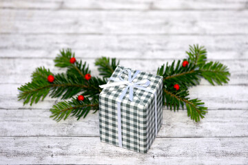 Geschenk, grüner Zweig, rote Beeren auf weißem Holz mit leerem Platz für Text als saisonaler...