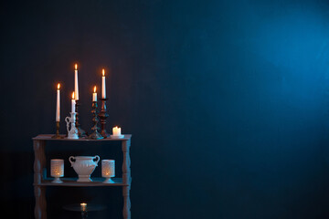 candlesticks with burning candles on  dark blue background - obrazy, fototapety, plakaty