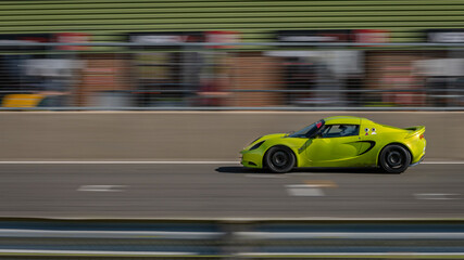 A panning shot of a green racing car as it circuits a track.
