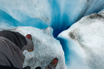 hombre al risco de un glacial con vista hacia el abismo
