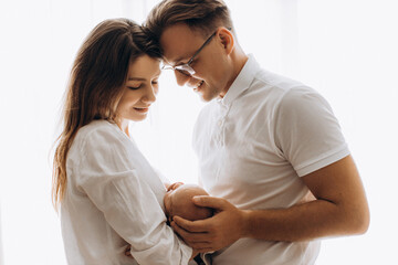 Lovely parents with newborn baby, loving mom hold little daughter in arms, caring dad gently touch...