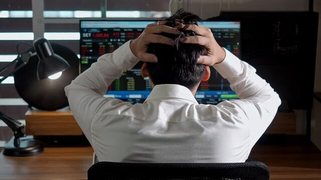 A man disappointed and sad that he loss the set market. Asian businessman monitoring stock market trading on computer at home office. 