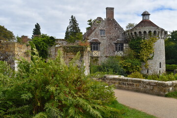 Fototapeta na wymiar Stone centuries old British medieval castle facade among greenery. It includes residential buildings dominated by great hall for feasting ceremonies place for holding judicial courts and estate office
