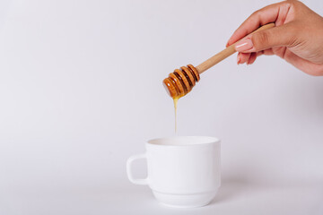 The girl's hand holds a Honey Dipper on a white Cup