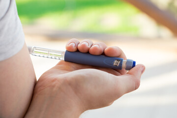 A diabetic patient using insulin pen for making an insulin injection at home. Young man control sugar diabetes. Diabetic lifestyle