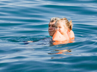 Grandfather and toddler girl in sea