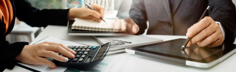Business people use tablets and hold credit cards as an online shopping concept With a calculator and a book placed on the table