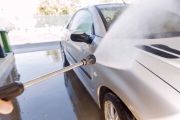 Washing car with pressure washer at self-service car wash station