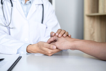Close up of doctor touching patient hand for encouragement and empathy on the hospital, cheering and support patient, Bad news, medical examination, trust and ethics