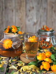 Herbal healthy marigold tea with a teapot, dried flowers on an autumn wooden background. Medicinal autumn background.