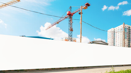 long hoarding with empty space for mock up on construction site red crane and blue sky background