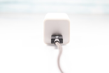 White charger adapter and black USB cable on a white background The concept of charging technology to power mobile phones