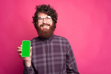 Cheerful young man holding the phone and smiling at the camera