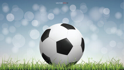 Fototapeta premium Soccer football ball on green grass field with light blurred bokeh background. Vector.
