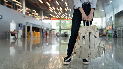 Girl  with backpack traveling in the airport. young woman hold bag in departure at the board terminals airport window. Concept travel