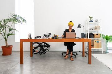 Shot of young latin woman working at home office with laptop and documents