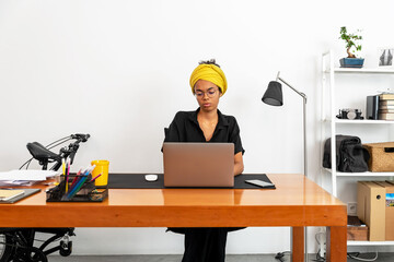 Shot of young latin woman working at home office with laptop and documents