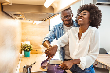 Shot of a young couple preparing a meal together at home. Happy young couple cooking together in the kitchen at home. Giving him a lesson or two in cooking