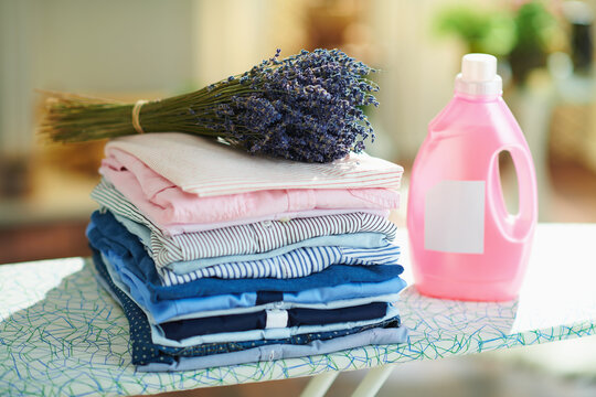 pile of clothes, softener and bunch of lavender on ironing board