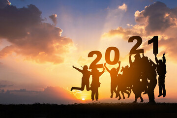 Silhouette of Business teamwork hands up and jump to the beautiful golden sky from text 2021...