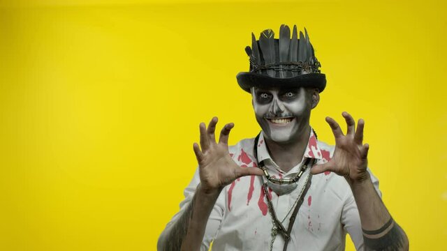Sinister man with horrible Halloween skeleton makeup trying to scare, pointing to the left