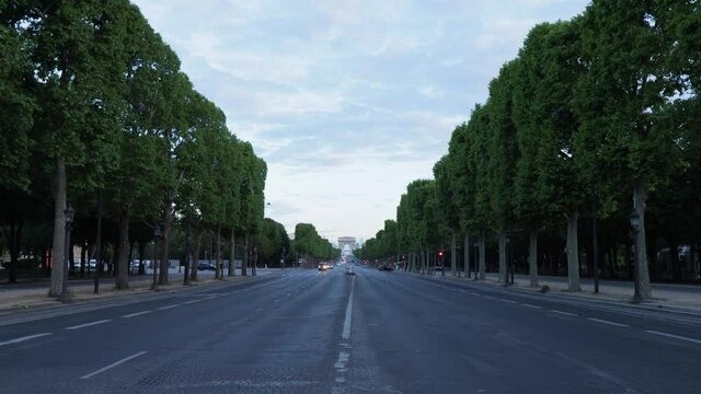 Champs-Elysees avenue empty in Paris with nobody and very few cars and triumphal arch in the background, wide dolly in shot during morning