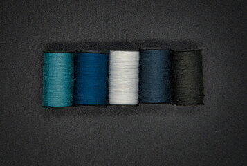Top view of colored sewing threads on black background. Sewing concept.