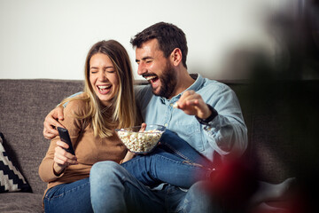 Wife and husband eating popcorn at sofa