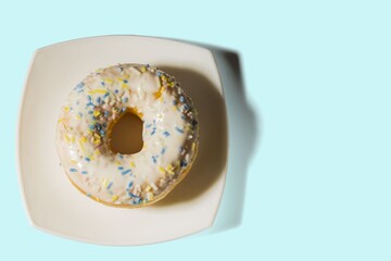 Close up view of sugar donut on white plate isolated on blue background.  Health and food background. 