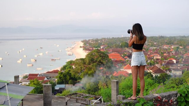 Travel photographer girl taking photos of ocean at sunset,Bali