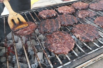Grilled burgers. Barbecue in the backyard. Fried meat on coals. American traditions.
