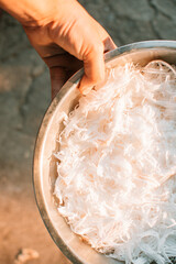 Hands holding fresh coconut flakes bowl. Natural white shredded coconut background.
