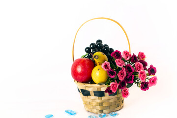 Floral composition with bouquet in basket and fruits on a white background.  Side view with copy space for your text. Studio shot.