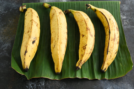 Many Kerala yellow banana or organic Ethappazham, nutritious ripe fruit used for making banana chips, fritters on green banana leaf background Tamil Nadu South India.