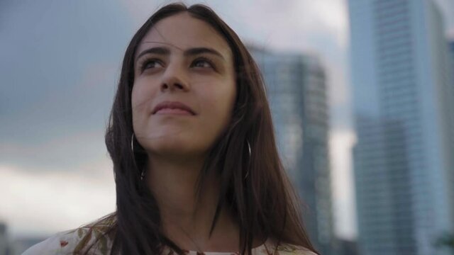Inspired confident business woman looks up at tall buildings and smiles, SLOW MOTION