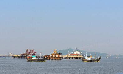 Boats moving near a Oil rig in the middle of the ocean