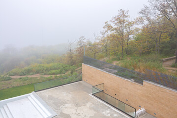Autumn fog in the park at cloudy day. Swimming pool without water during the off-season.