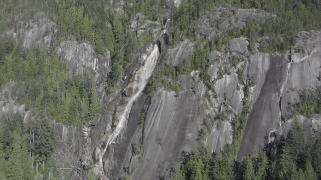 Quiet breathtaking stunning aerial hold close up of the mountain side of icy rushing waterfalls coming down ythe cliff covered trees of Shannon Falls BC Squamish in the summer. 2-5