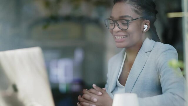 African american business lady with earphones videochatting laptop computer conference social media remote communicating passing job interview sitting in the cafe.