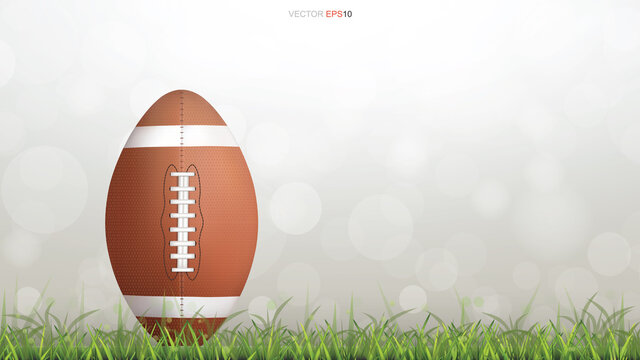 American football ball or rugby football ball on green grass court with light blurred bokeh background. Vector.