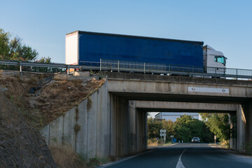 Fototapeta na wymiar Truck driving over a bridge with a road underneath