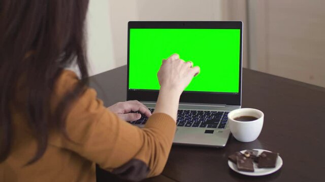 Woman working and typing on the laptop and eating chokolate. Work at home