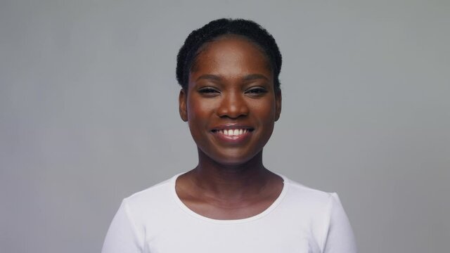 people, ethnicity and portrait concept - happy african american young woman over grey background